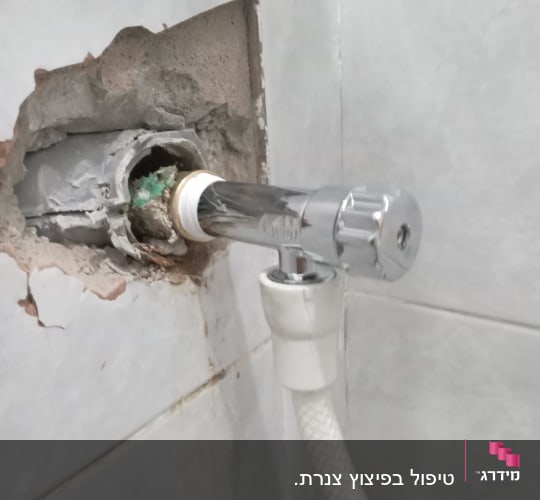 ברז מתכת מותקן בקיר עם צינור לבן